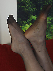 Mature nude tease on red couch with natural tits and stockings